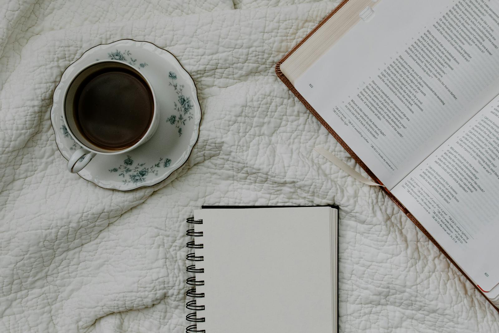 Taza de té, Biblia abierta y libreta sobre una mesa - momento de fe y reflexión