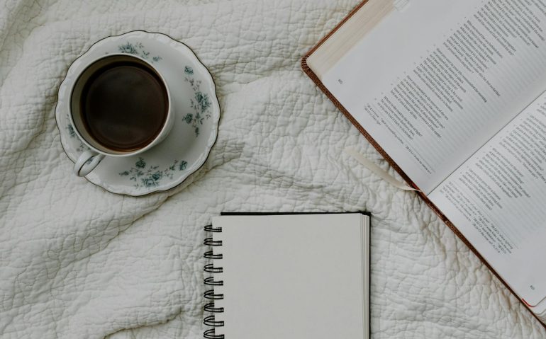 Taza de té, Biblia abierta y libreta sobre una mesa - momento de fe y reflexión